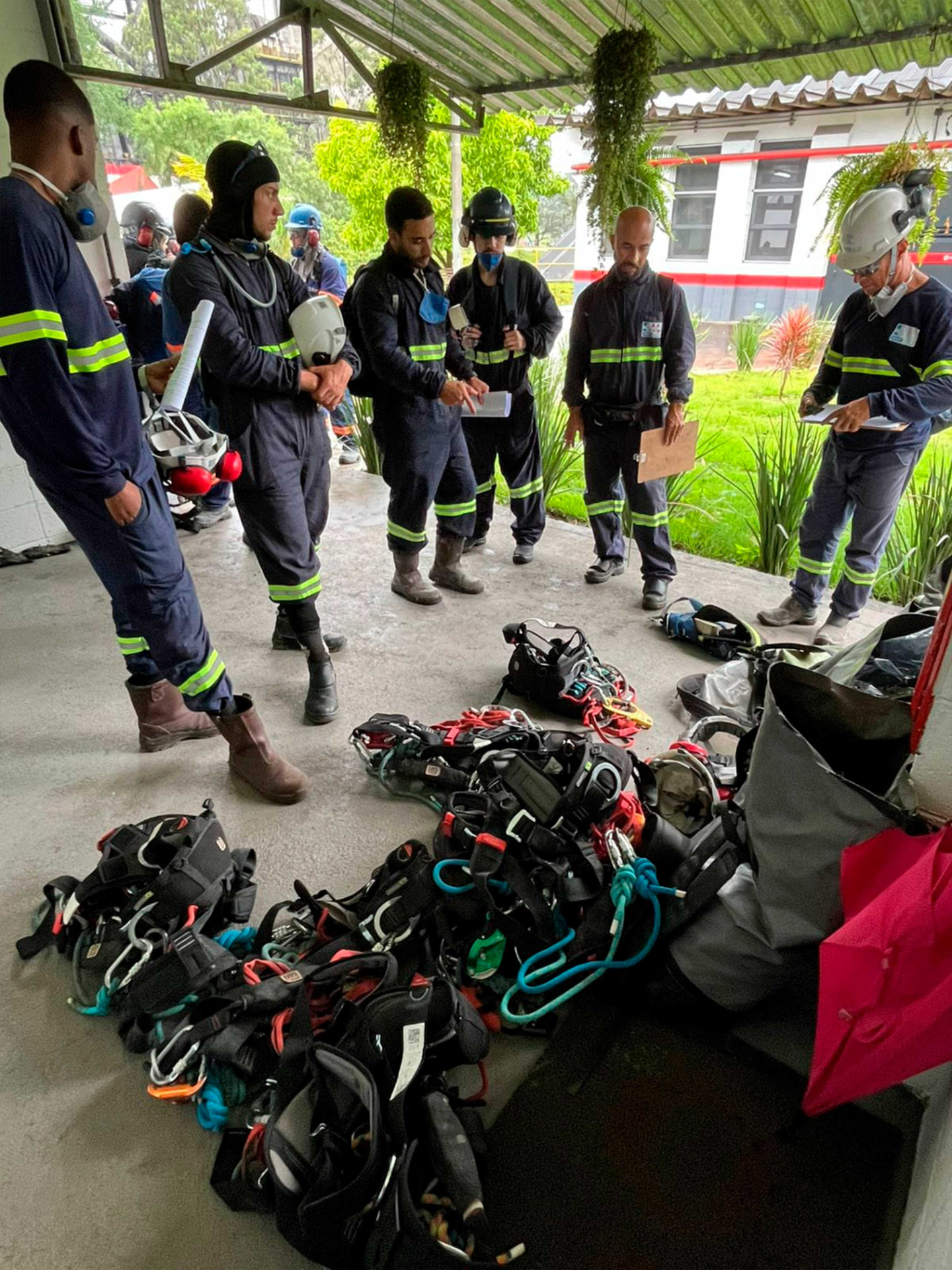Equipe técnica com EPI reunida junto a equipamentos de acesso antes da execução