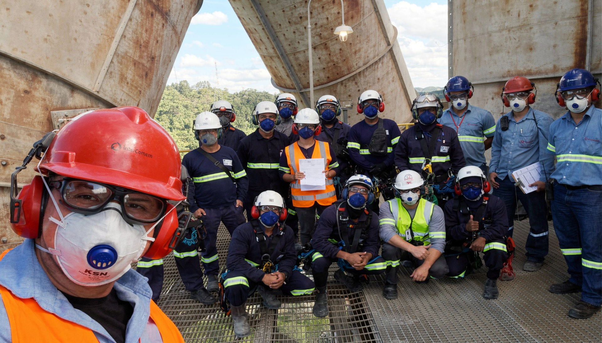 Equipe técnica da DM com EPI completo reunida em plataforma de planta industrial