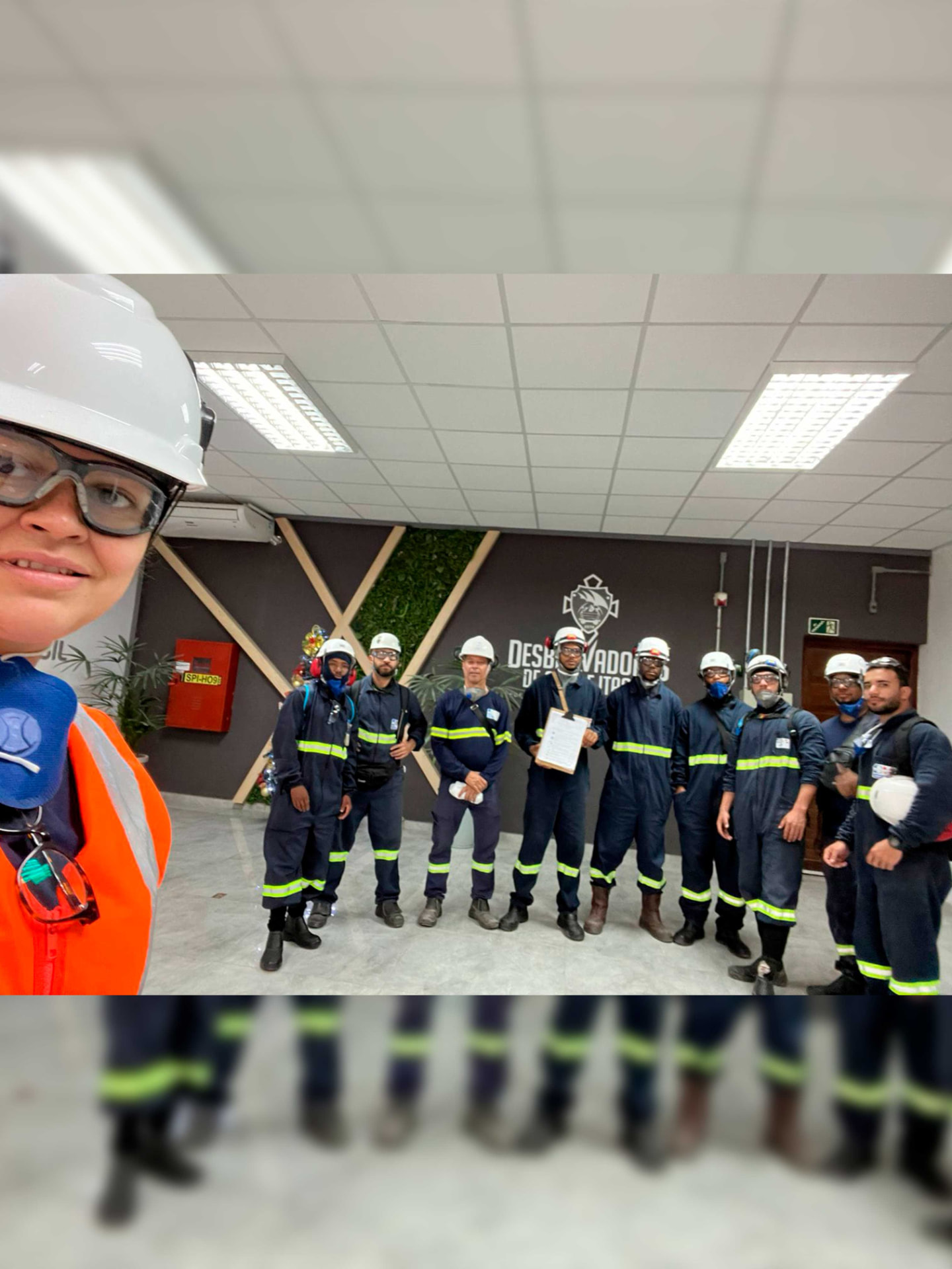 Equipe técnica uniformizada com EPI reunida em área interna de planta industrial
